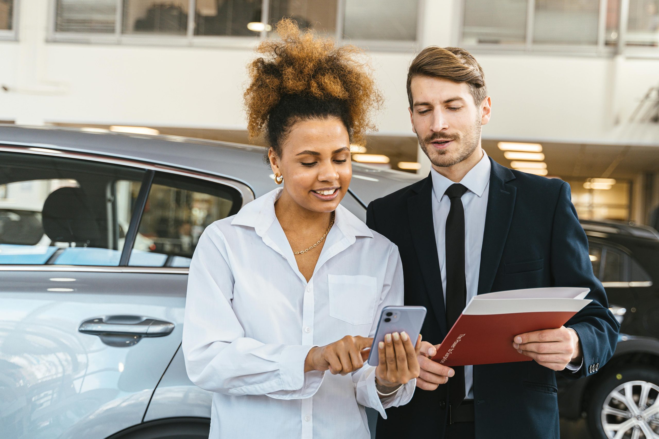 People Looking at a Mobile Phone Beside a Car