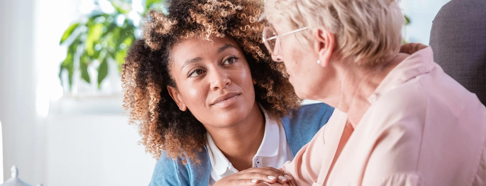 Woman holding an elderly woman's hand and looking into her eyes
