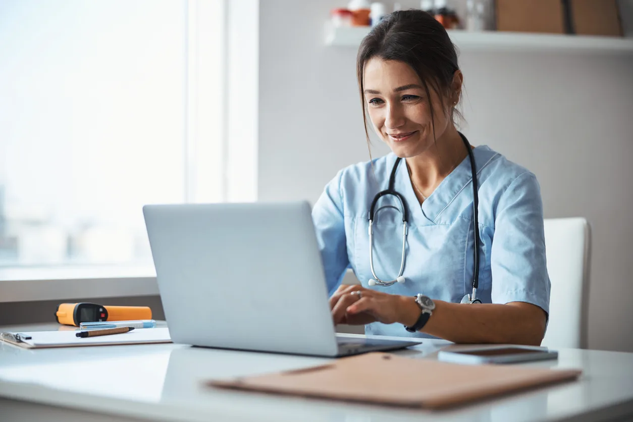 Joyful female healthcare worker using notebook in clinic