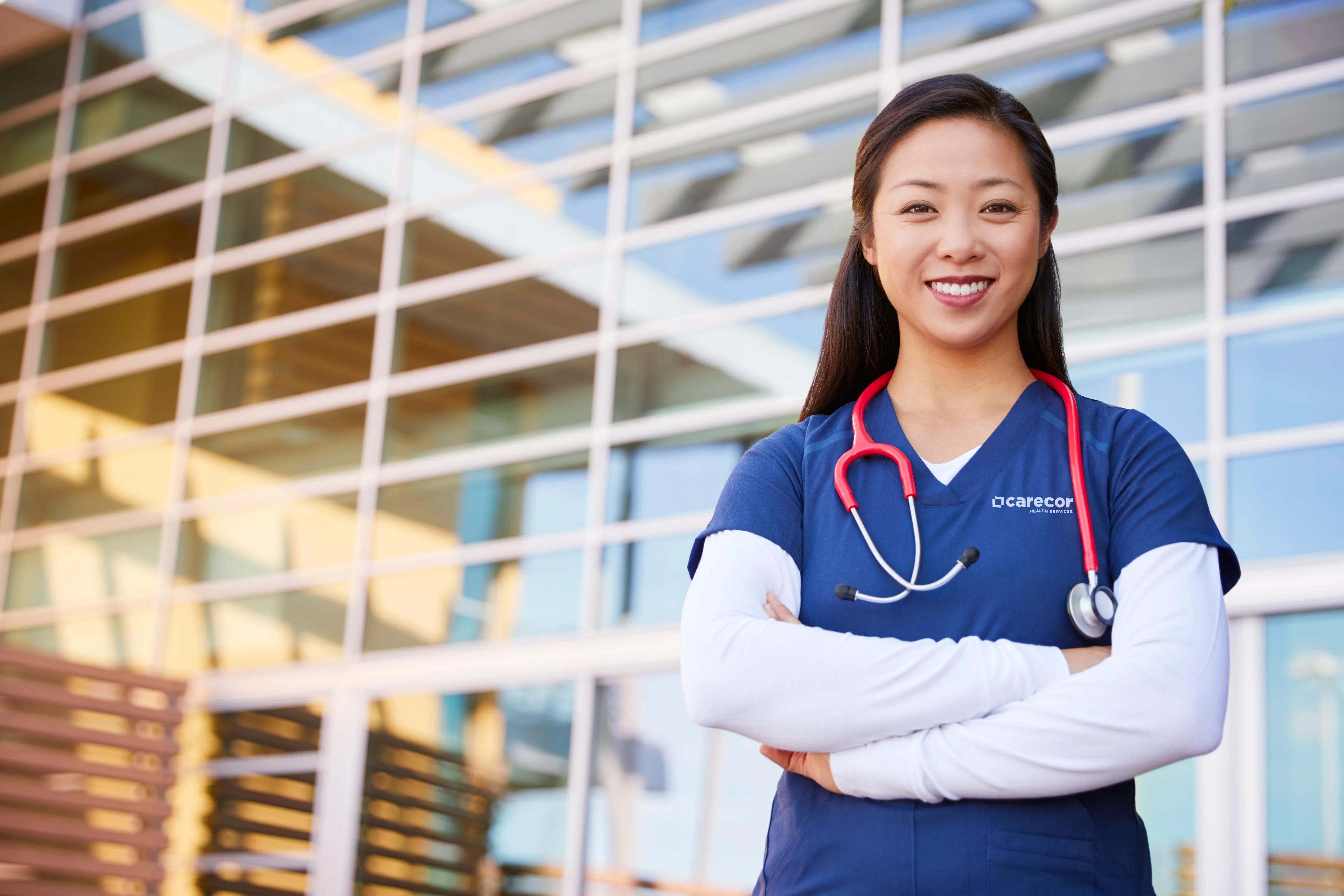 Smiling Asian female healthcare worker with arms crossed
