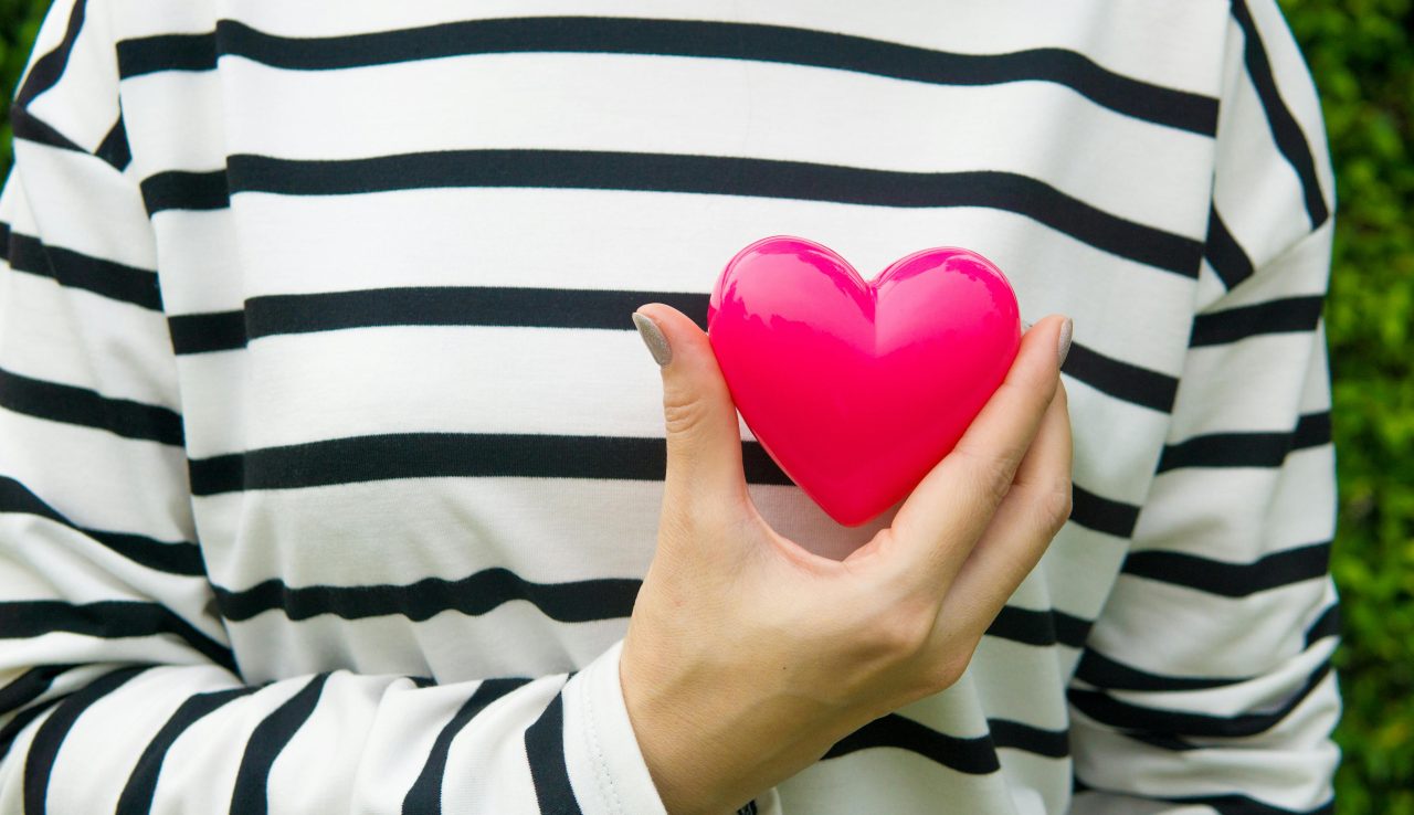 Woman holding heart over a black and white striped sweater