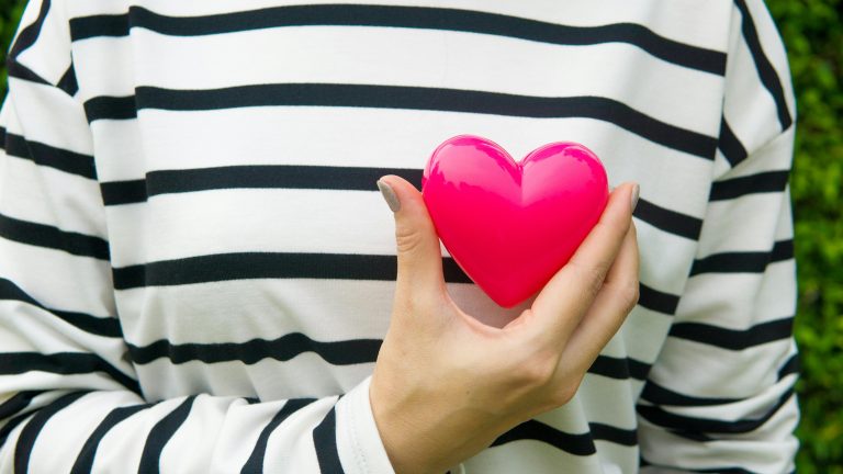 Woman holding heart over a black and white striped sweater