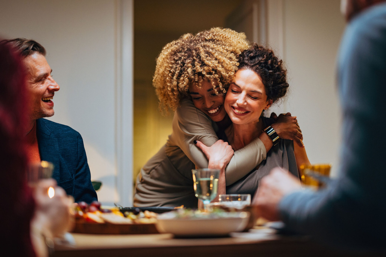 Two Friends Hugging During A Dinner Celebration